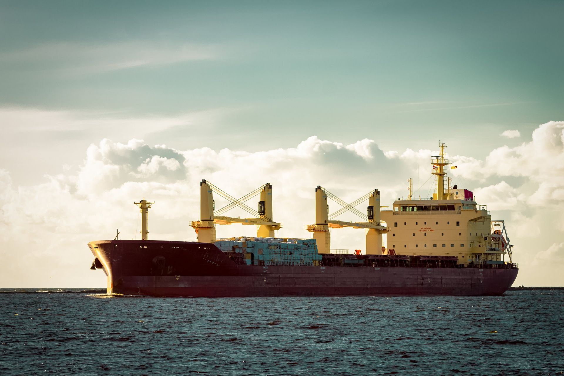 General cargo vessel with deck cranes at sea
