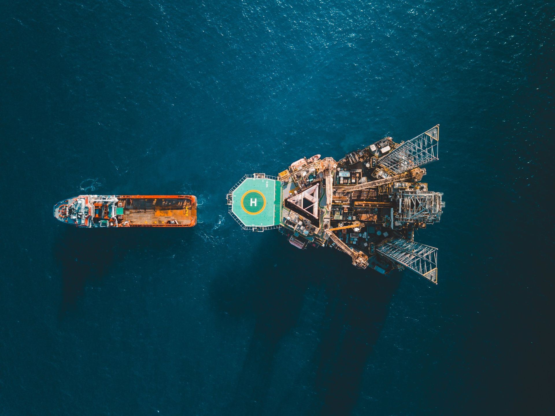 Aerial view of an offshore supply vessel alongside a jack-up rig