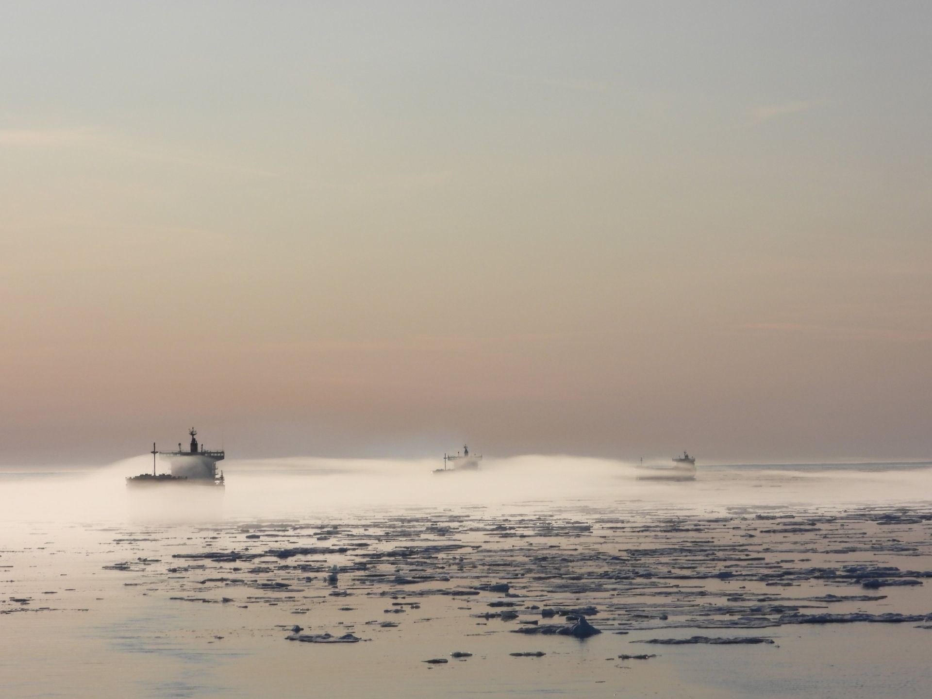 Vessels in sea smoke among drifting ice floes